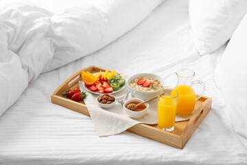Wooden tray with tasty breakfast on bed