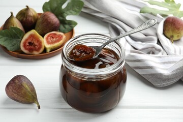Jar of tasty sweet jam and fresh figs on white wooden table