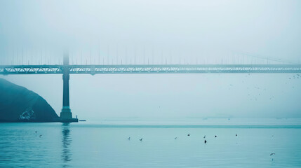 A misty scene with a bridge obscured by fog over a calm body of water with birds and subtle hints of land