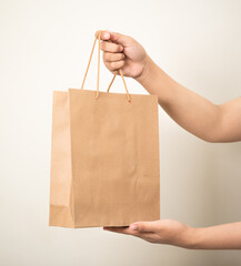 hand holding a shopping paper bag against a white isolated background