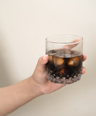 hand is holding a glass of coffee with ices on a white isolated background