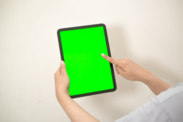 hand is holding a tab with green screen on a white isolated background