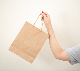 hand holding a shopping paper bag against a white isolated background