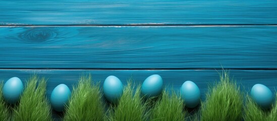 Colorful Easter eggs hidden among the lush green grass on a vibrant electric blue wooden...