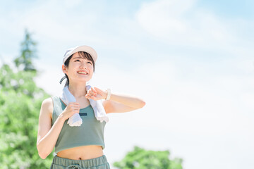 公園でスマートウォッチを見ながら運動・トレーニング・ウォーキングする女性(時間・タイム・ヘルスケア)
