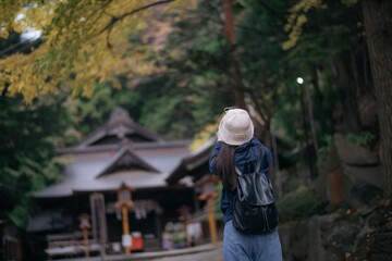 Asian woman discovers the spiritual essence of Japanese shrines and temples, radiating happiness,...