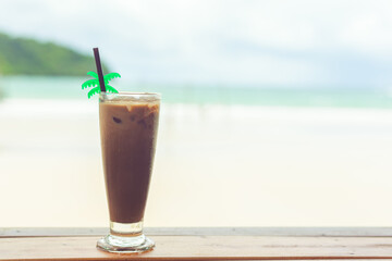 Cold cocoa in a glass on a wooden table by the sea in summer