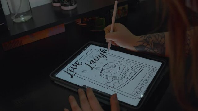a tattoo artist  with a flowered wrist tattoo sketches a design for a tattoo she draws it first on her electronic tablet