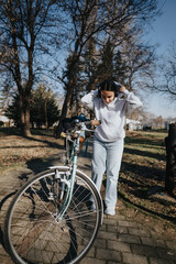 Active woman with headphones preparing for a bike ride in the park.