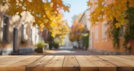 Foto op Canvas Golden autumn leaves scattered on a rustic wooden table with a blurred foliage background. © tashechka
