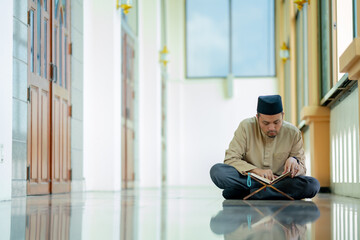 Ramadan, Quran, Islam,  An Asian Muslim man is sitting and reading the Quran. The peace in the mosque makes it an energetic atmosphere of faith, with copy space.