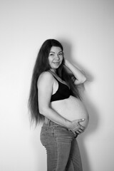 36 weeks pregnant. Long-haired Caucasian pregnant woman in jeans. Big belly. Body positive. Black...
