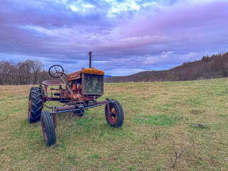 Old abandoned tractor in the field at sunset