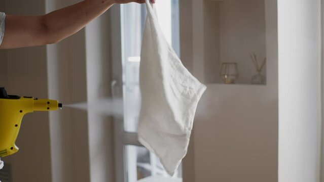 Cropped shot of unrecognizable young man working hot wet steam on pillowcase using modern electric steam cleaner ay home. Concept of cleanliness and housekeeping. Shooting in slow motion.