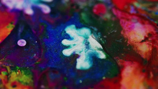 Paint drop. Glitter ink mix. Defocused colorful sparkling particles texture fluid emulsion blend splash motion abstract art background.