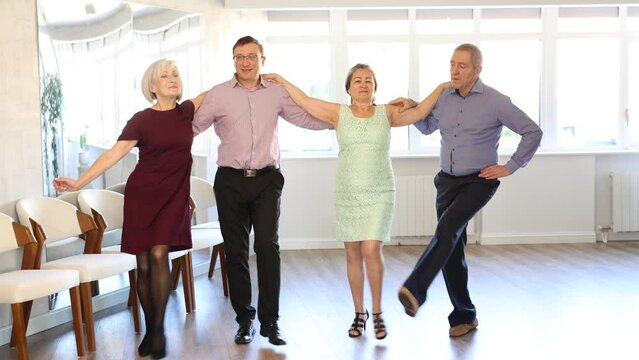 Group men and women dancing folk dance in row in studio