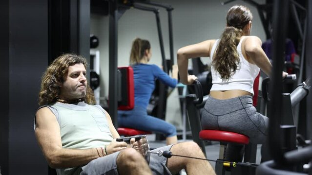 Caucasian man is engaged in a simulator with horizontal weights in the gym. High quality 4k footage