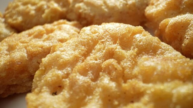 A chicken nugget is a small, breaded, and deep-fried piece of chicken meat, often served as a fast food snack, known for its crispy exterior and tender interior. Fast-food background. 4K HDR.
