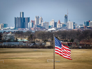 An image of the American Flag with the Detroit skyline in the background