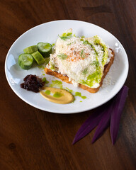 Avocado Egg Toast with Sauce, Garnished with Fresh Herbs and Served with Cucumber Slices and Mustard.
