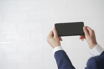 Close-up of a woman in a suit holding a cell phone on a white background
