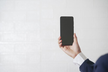 Close-up of a woman in a suit holding a cell phone on a white background