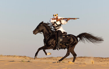 Saudi man in a desert, riding a black stallion, shooting a hunting rifle
