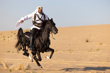 Saudi man in a desert with his black stallion
