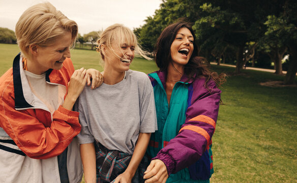 Three female friends having a fun day out in the park, laughing and socializing