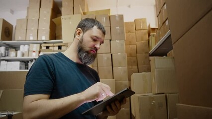 Handsome warehouse worker uses digital tablet for checking stock