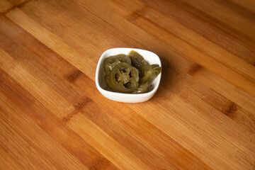 Jalapeno pickled preserved served in plate isolated on wooden table top view of indian food