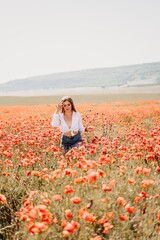 Obraz na płótnie Canvas Woman poppies field. Back view of a happy woman with long hair in a poppy field and enjoying the beauty of nature in a warm summer day.
