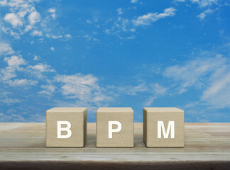 BPM acronym on wood block cubes on wooden table over blue sky with white clouds, Business process...