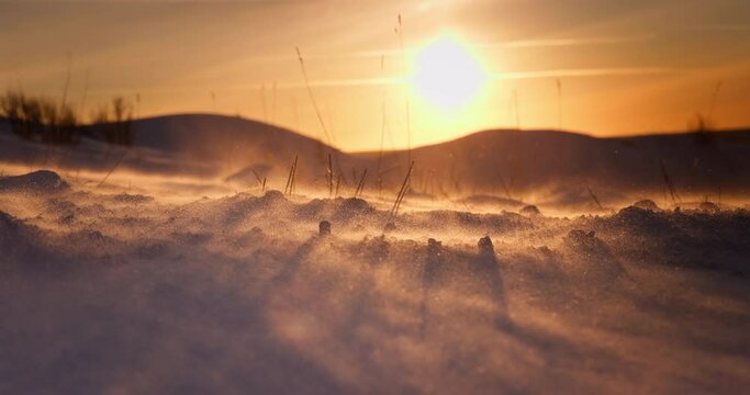 Frozen landscape of snow covered field after a blizzard, ice desert, winter wonderland, wind blows snowflakes, morning sunlight, polar sunrise 4K cinematic video