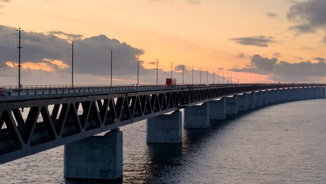 Vibrant sunset sky with traffic moving over iconic Oresund bridge. Aerial riser