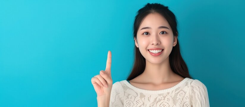 Asian beautiful woman pointing one hands with finger on upper side with smile face on pastel background in studio. copyspace and presentation concept