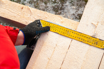 A man in a red jacket is engaged in construction using wooden planks - 755389225