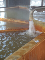 Japanese onsen hot spring bath with hot thermal water flowing from fountain