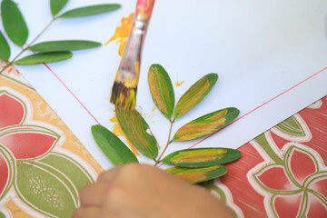 kid painting on leaf in learning eco print idea activity