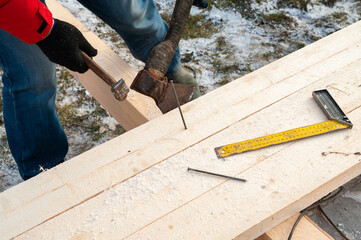 A man in a red jacket is engaged in construction using wooden planks - 755390052
