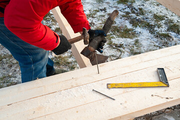 A man in a red jacket is engaged in construction using wooden planks - 755390260