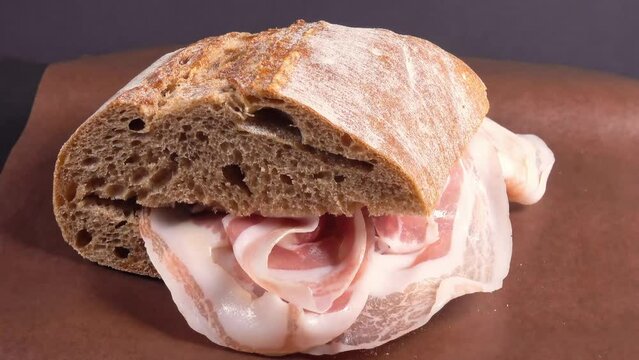 ciabatta sandwich with sliced ham, on paper, rotating