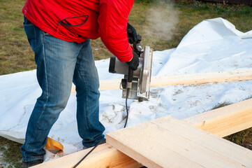 A man in a red jacket is engaged in construction using wooden planks - 755391276