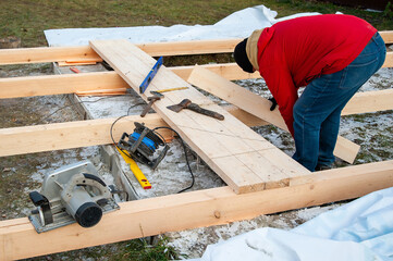 A man in a red jacket is engaged in construction using wooden planks - 755392241