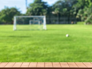 Empty wooden table with blurred of small soccer field background for showing food, drinks, products