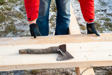A man in a red jacket is engaged in construction using wooden planks - 755396892
