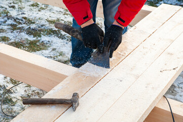A man in a red jacket is engaged in construction using wooden planks - 755397207