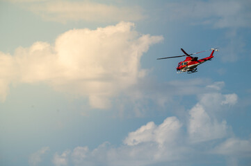 Fototapeta na wymiar Red helicopter flying with clouds