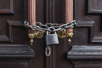 Locked wooden door with a lock hanging on a chain