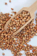 
De hulled buckwheat with wooden scoop on white
